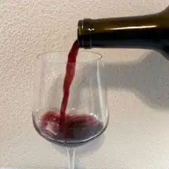 pouring a glass of red wine before adding salt
